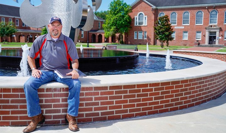 Wounded warrior and peer support group leader Deron Santiny sits on the wall of a large fountain at the University of Louisiana Lafayette. 