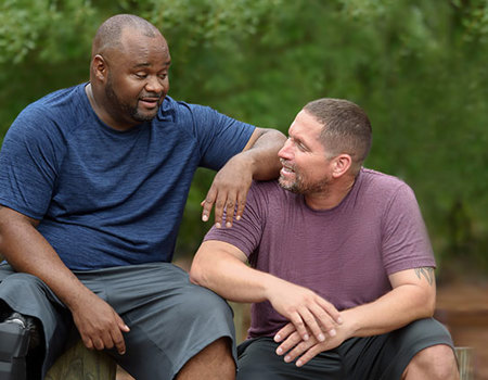 Warrior Chris Gordon sits next to fellow wounded Warrior Manny Colon while talking.