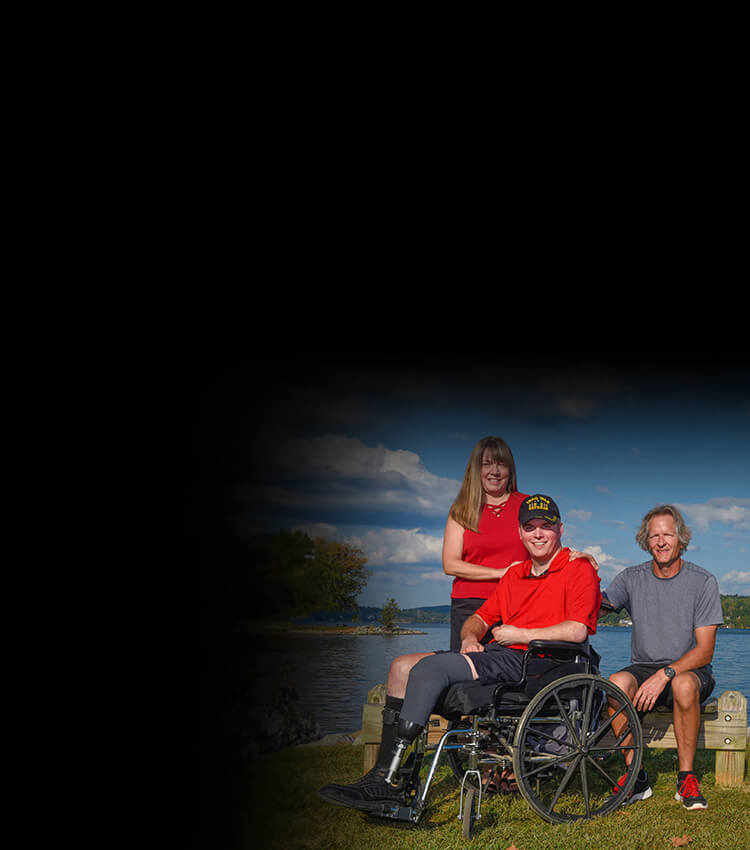 Wounded warrior Jason Ehrhart sitting outside in a wheelchair with his parents