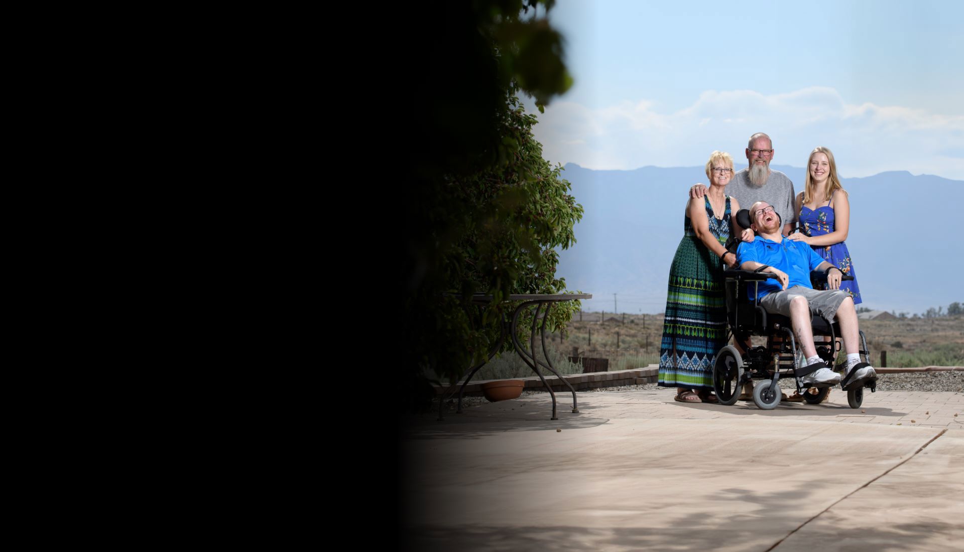 Wounded warrior Erik Schei with his parents and sister smiling in front of mountains. Erik is in a wheelchair.