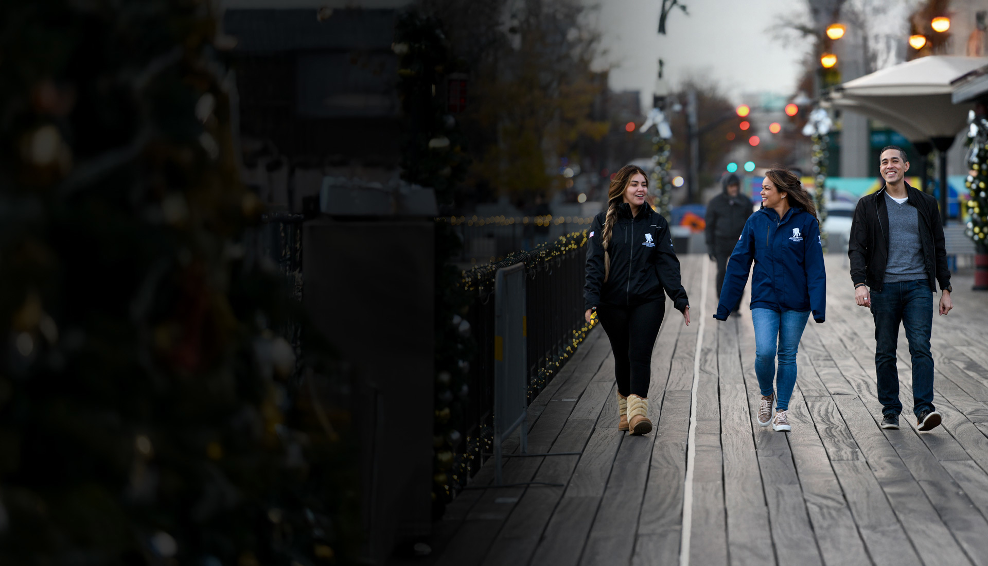 Wounded warriors Rochelle Santiago, Antoinette Wallace, and Sergio Alfaro talk with each other and walk along a boardwalk with holiday decorations.