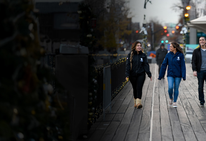 Wounded warriors Rochelle Santiago, Antoinette Wallace, and Sergio Alfaro talk with each other and walk along a boardwalk with holiday decorations.