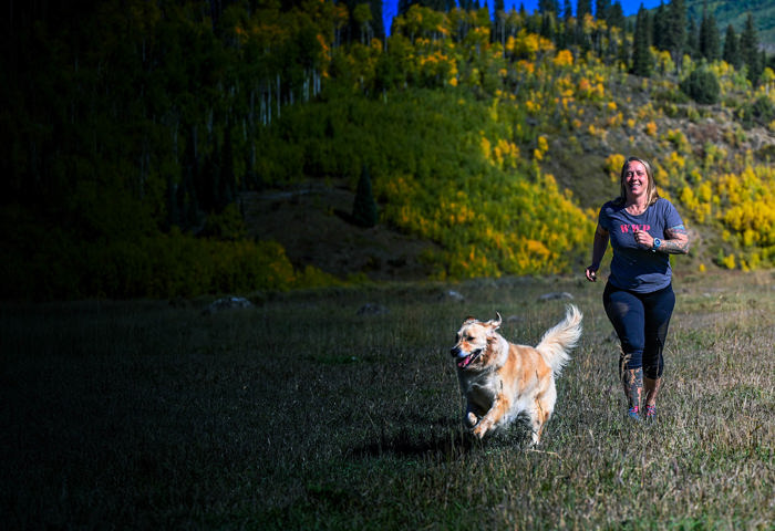 Wounded warrior Angie Peacock and her dog, running through the grass.