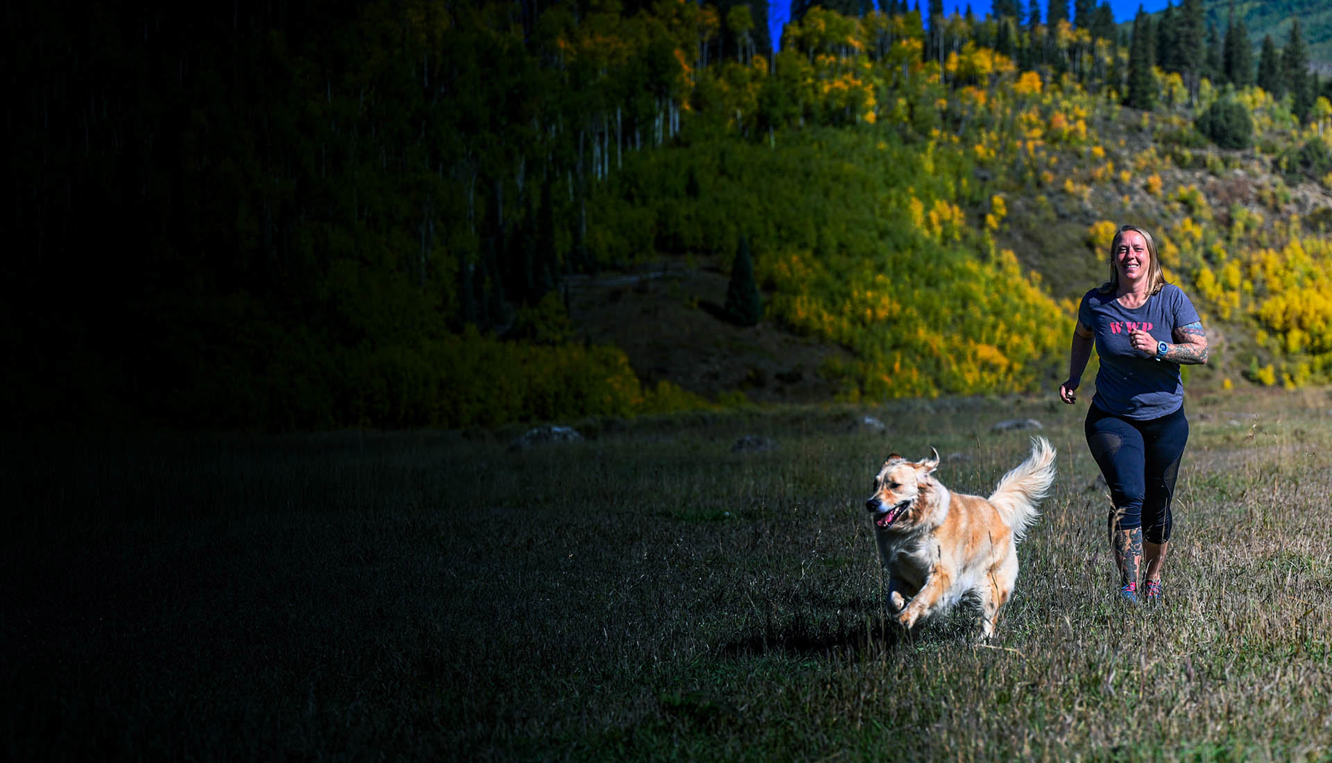 Wounded warrior Angie Peacock and her dog, running through the grass.