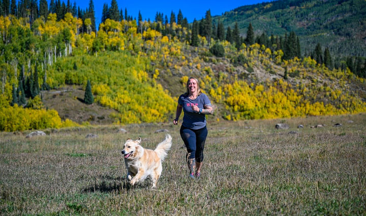 La veterana herida Angie Peacock corriendo en un campo con su perro de servicio.