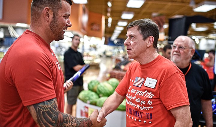 A wounded warrior shakes hand with a volunteer at an event.