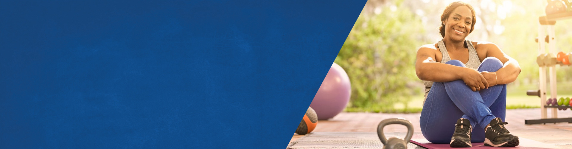 Wounded warrior Yolanda Poullard sits on a yoga mat with her legs crossed, surrounded by various workout gear, such as weights and exercise balls.