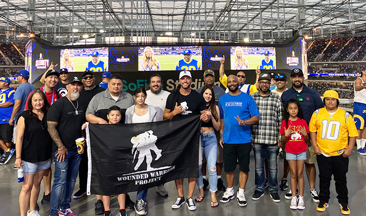 A group of warriors gather for a photo on the concourse while holding a WWP flag at SoFi stadium in Los Angeles, CA before an LA Rams game.