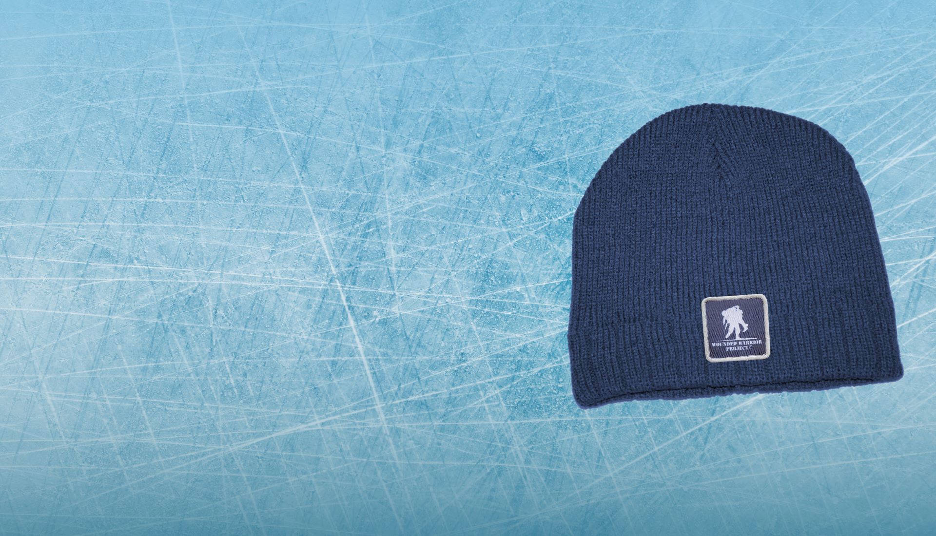 Navy blue knit beanie hat with white Wounded Warrior Project logo patch. Light blue ice graphic background image.