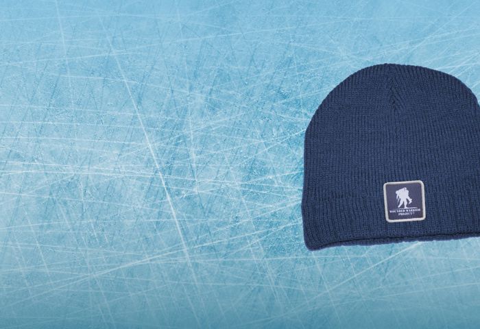 Navy blue knit beanie hat with white Wounded Warrior Project logo patch. Light blue ice graphic background image.