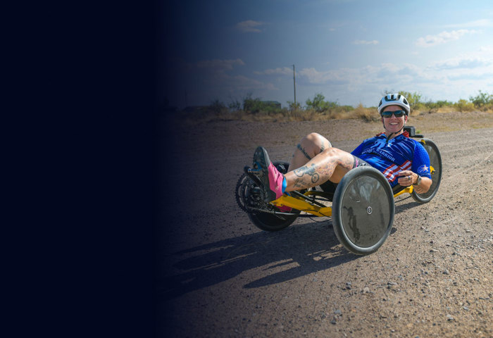 Wounded warrior Beth King trains for Soldier Ride on a recumbent bike on a gravel road.