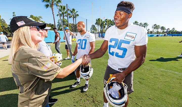 A San Diego Chargers players shakes hands with a woman warrior during a pre-season training camp practice.