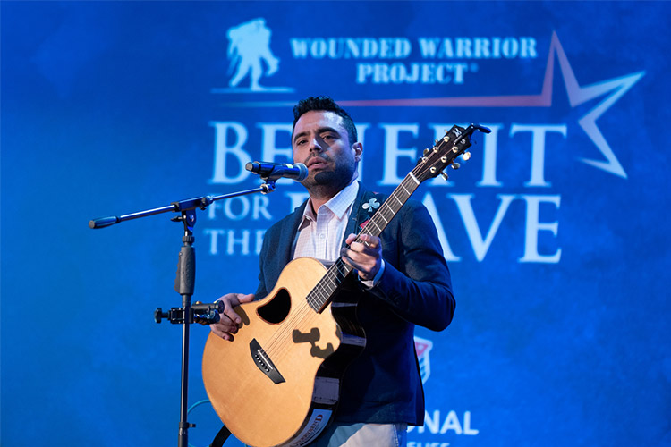 El veterano herido de WWP, Sal Gonzalez, canta con una guitarra en el evento WWP Benefit for the Brave.